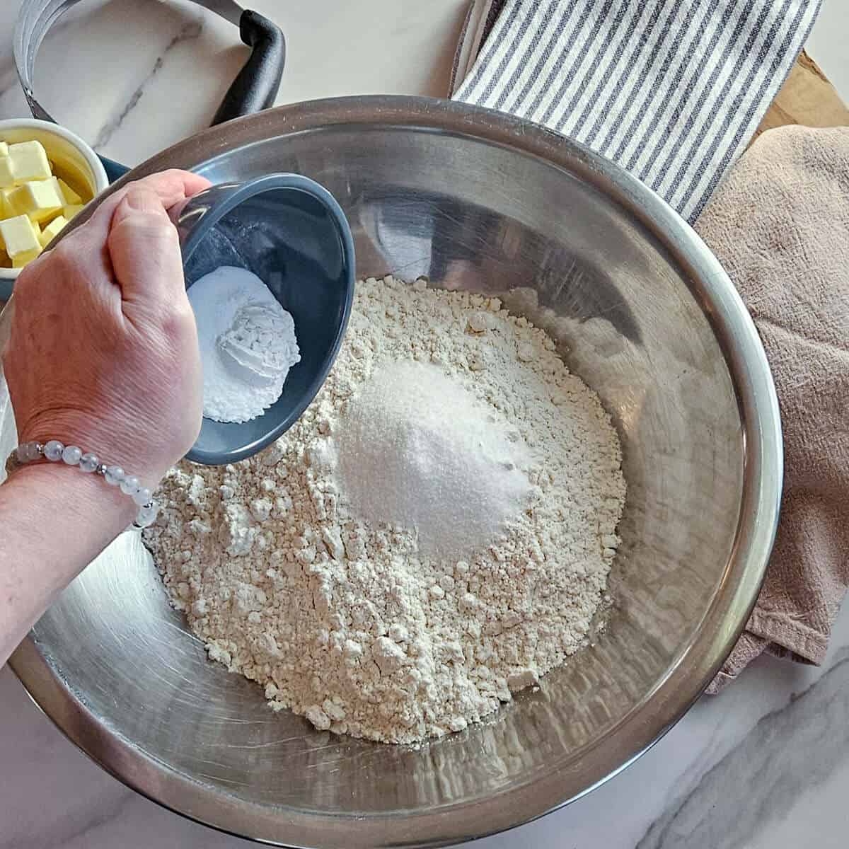 an image of adding the baking soda and baking powder to the bowl containing the gluten free flour, sugar, and salt for the gluten free Irish soda bread