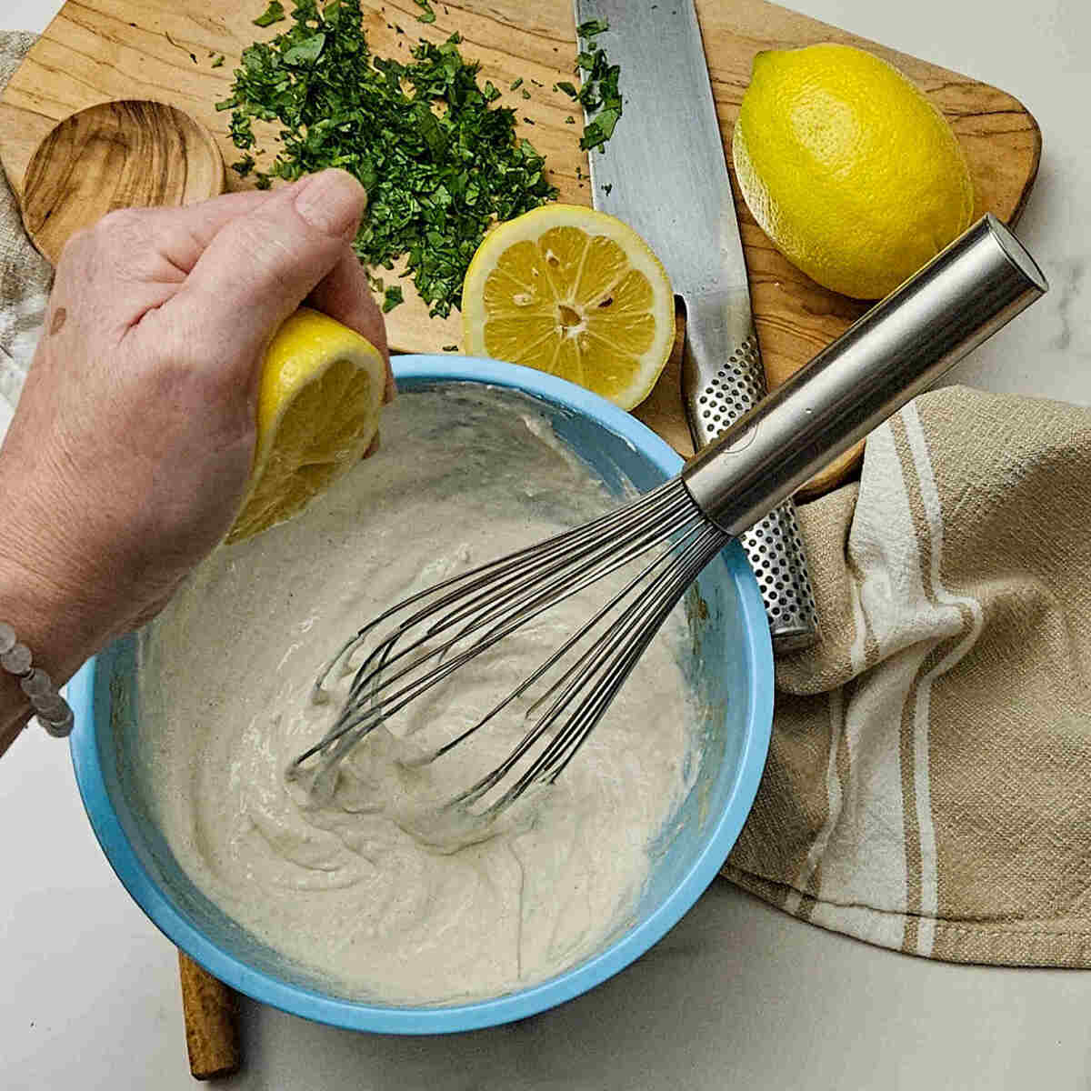 an image of squeezing a half of a lemon into a bowl with the best creamy horseradish sauce