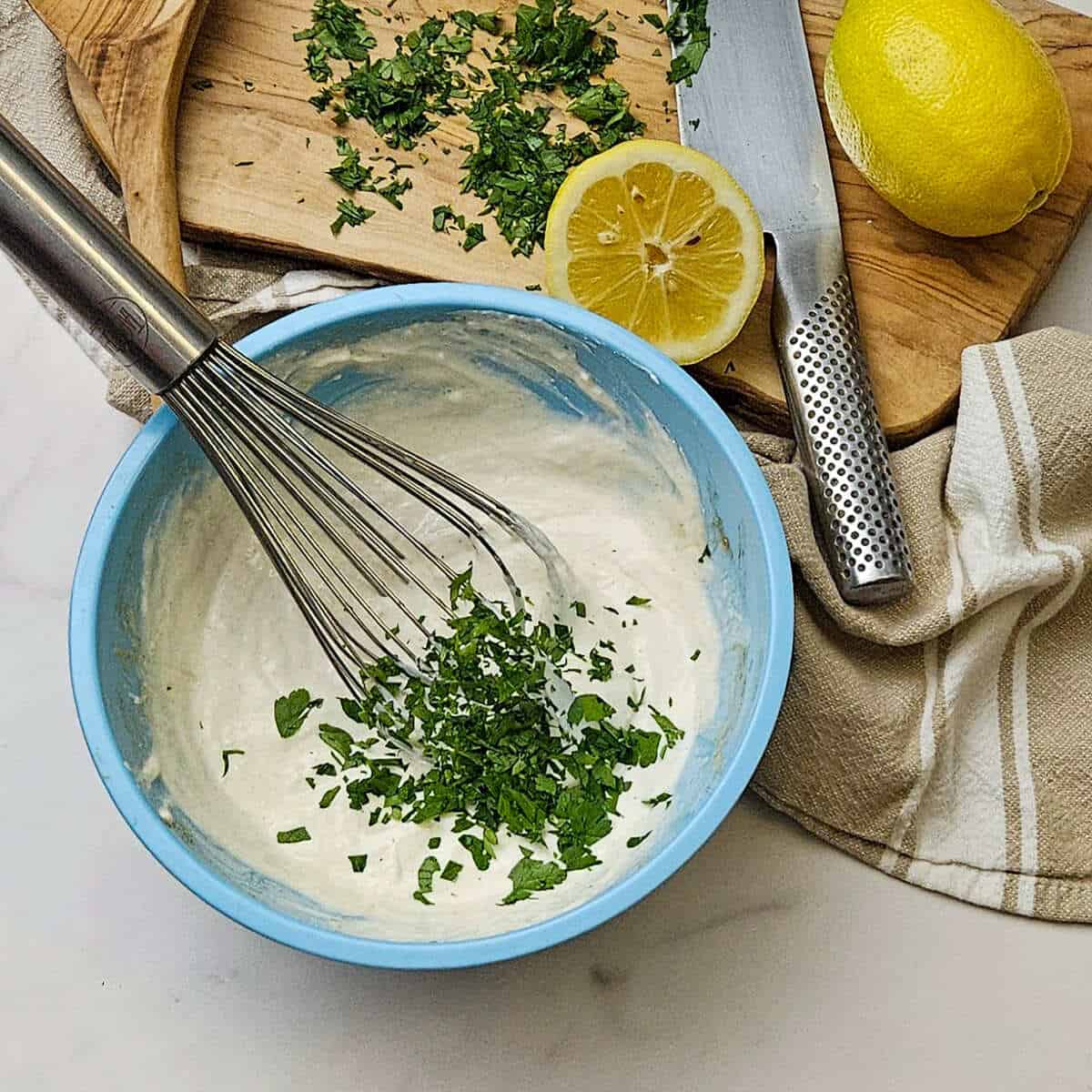 an image of adding the chopped parsley to the bowl with best creamy horseradish sauce