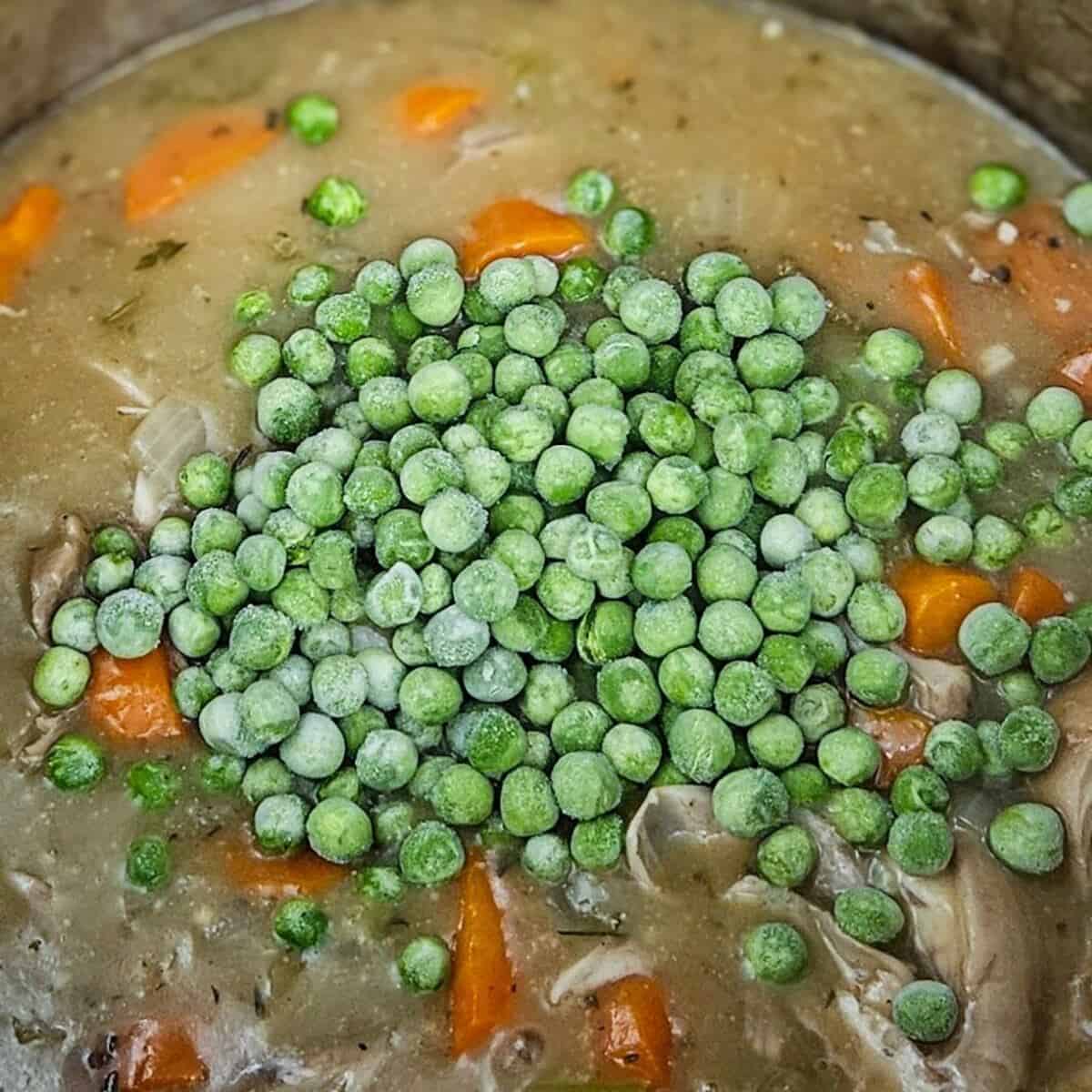 adding frozen peas to the filling for chicken cottage pie recipe