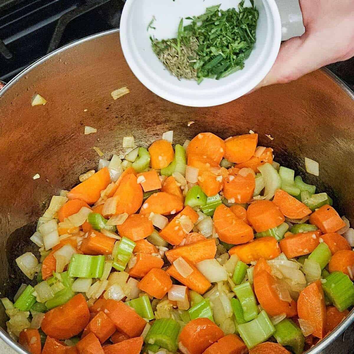 adding chopped herbs to the vegetables and garlic for the filling for chicken cottage pie