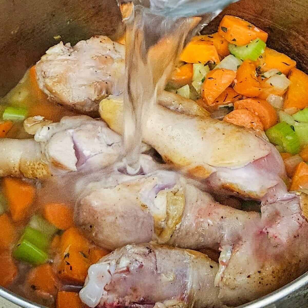 adding water to the chicken legs and vegetables for the chicken cottage pie