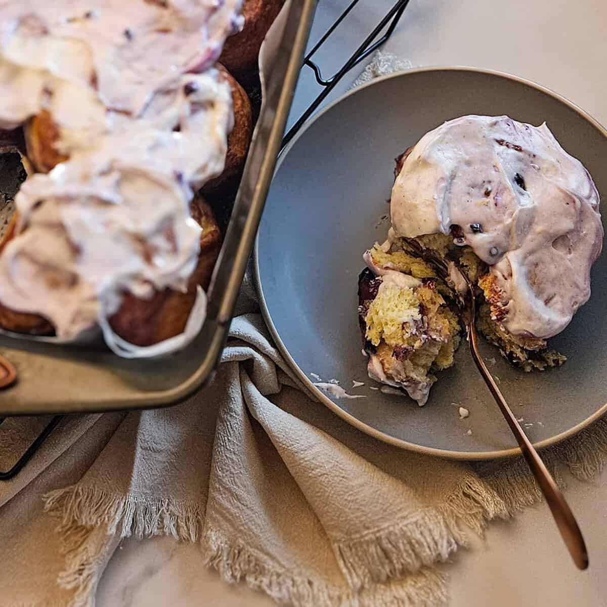 close up of brioche blueberry cinnamon rolls on a plate with a fork