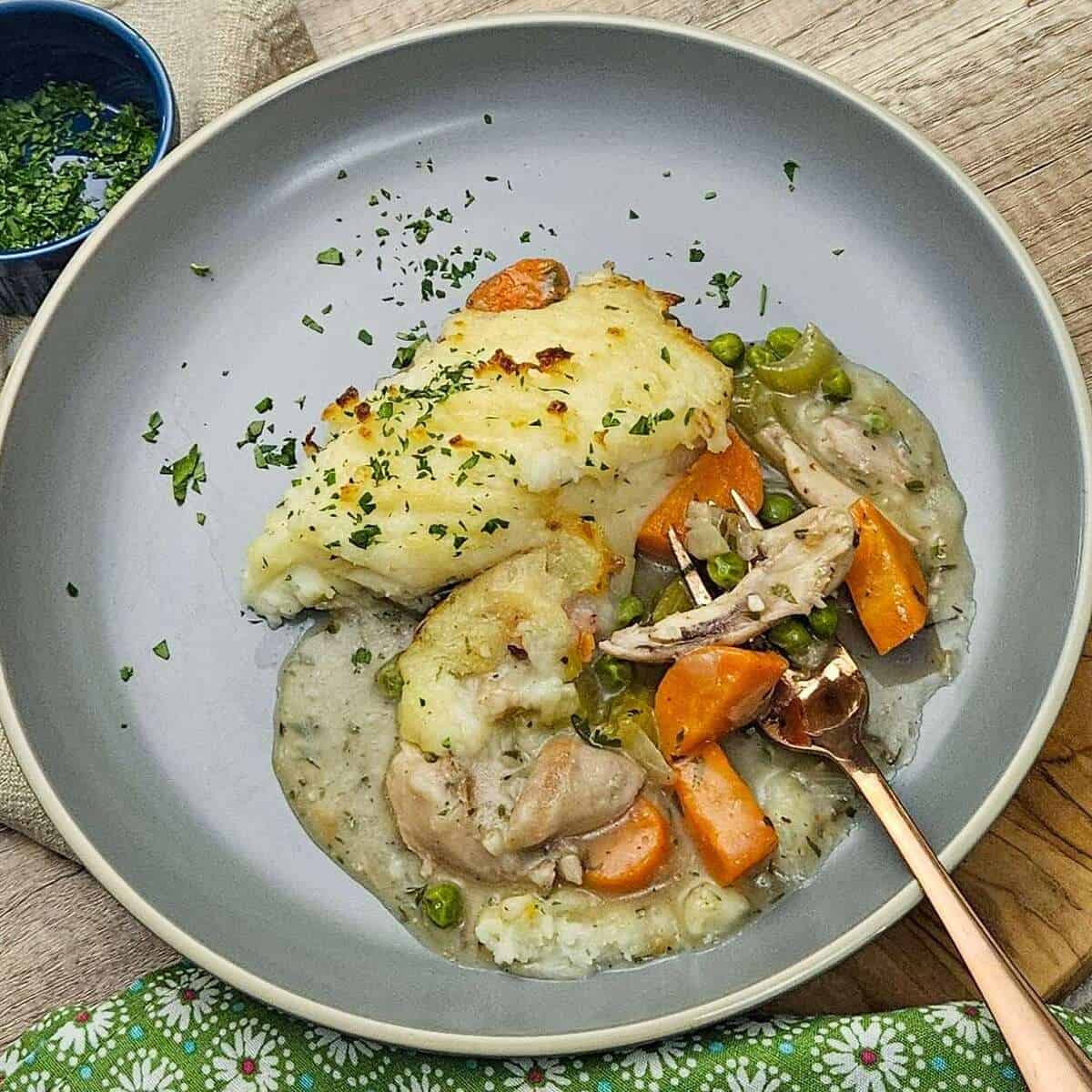 a serving of chicken cottage pie on a plate garnished with chopped parsley