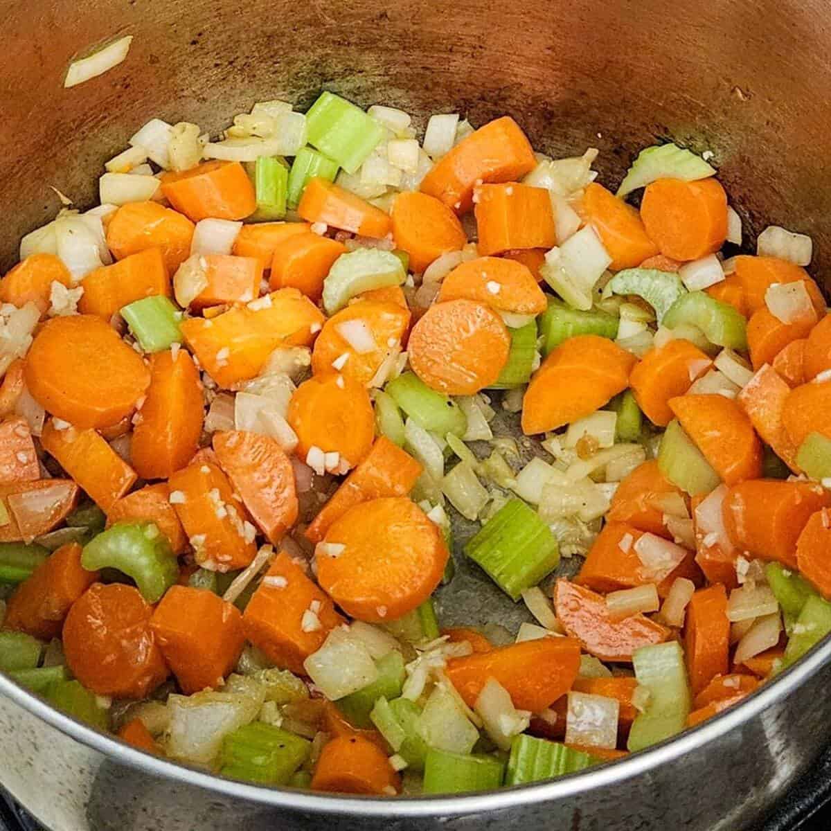 cut up carrots, celery, and onions, with garlic cooking for the chicken cottage pie