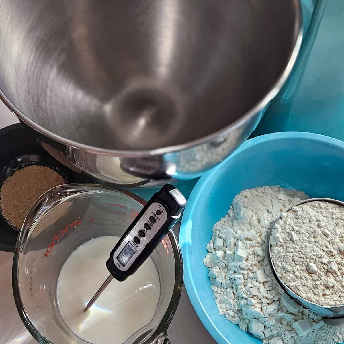 the ingredients for the sponge with a thermometer in a cup of milk, for the brioche blueberry cinnamon rolls