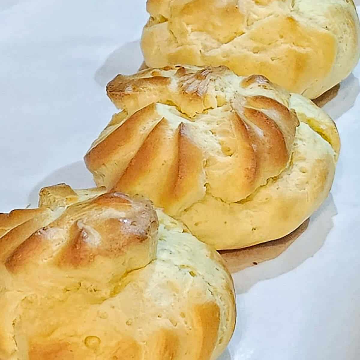 cream puffs fresh out of the oven on a baking sheet pan