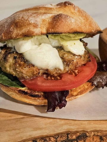 a grilled caprese basil pesto chicken burger on a bun with tomato and lettuce ready to eat