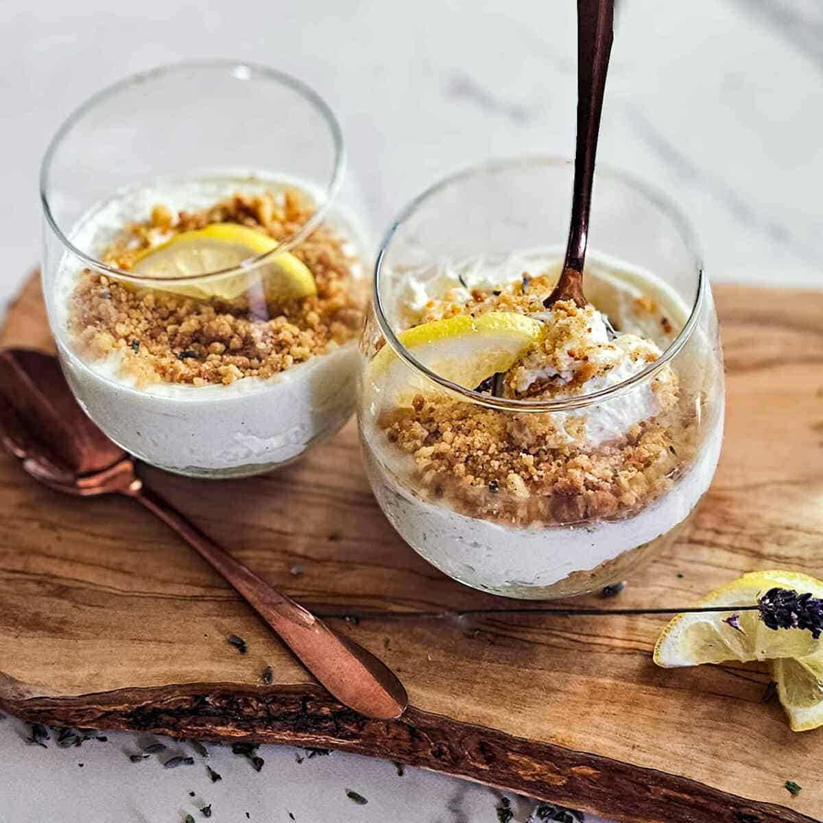 glasses filled with lemon cheesecake, topped with gluten free crumbs.