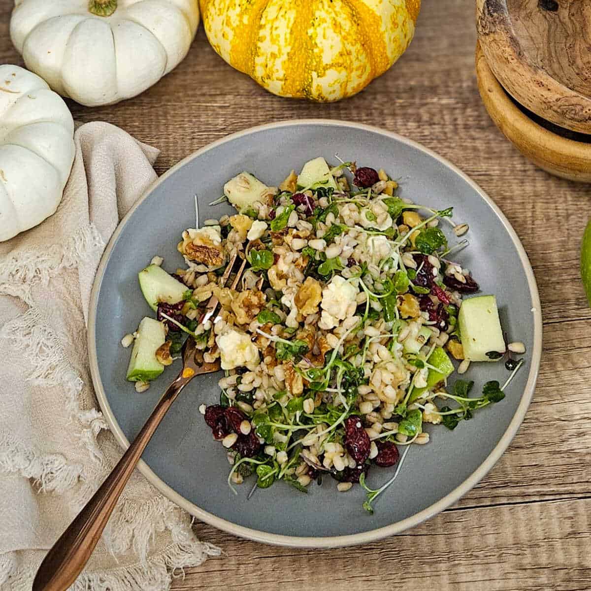 plate of apple and barley salad with a fork and micro greens.