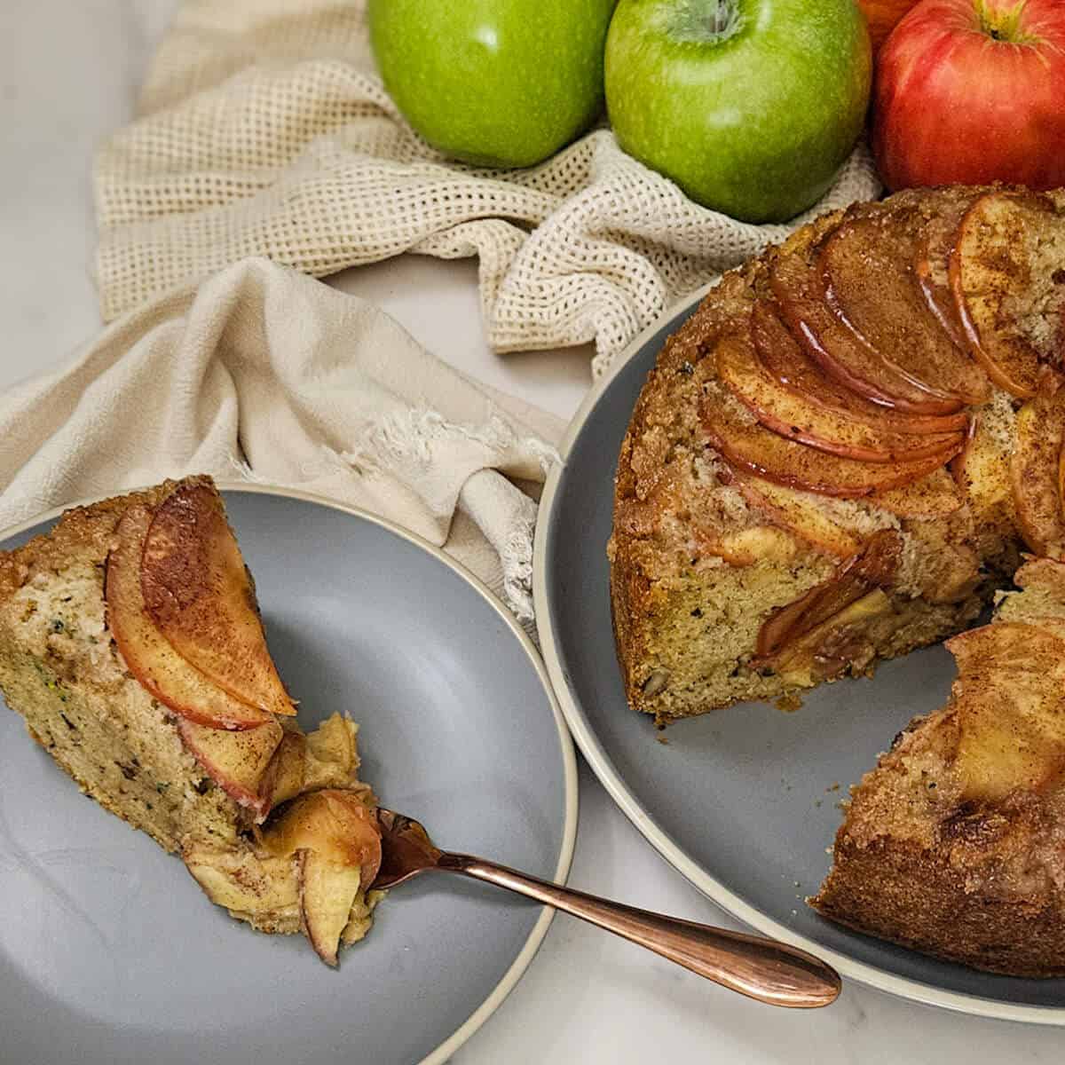 round zucchini bread with fanned apples on top with a slice taken out and plated.