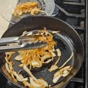 Removing the browned onions from the pan for the white cheddar and bacon zucchini bake.