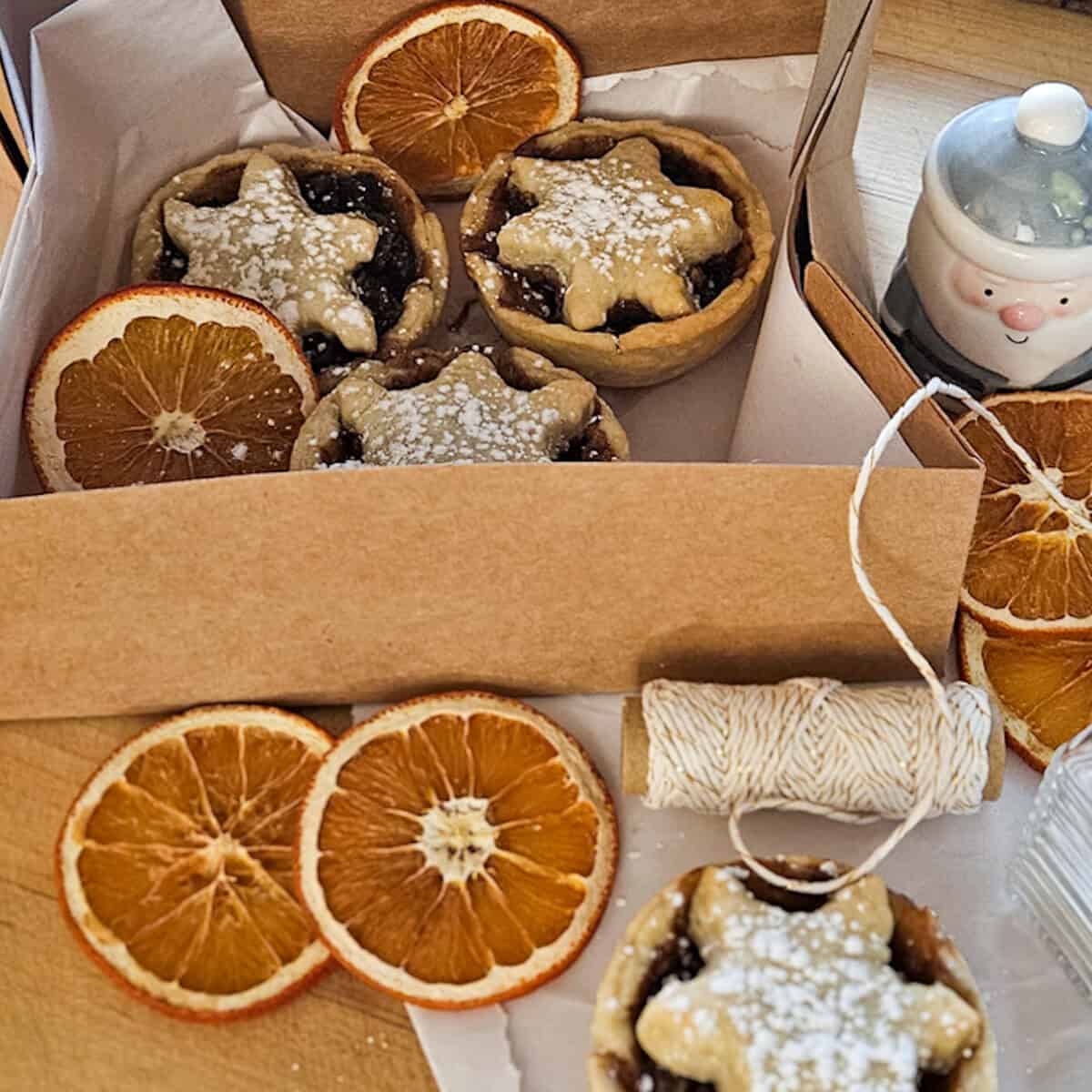 Mincemeat pies in a box with dried orange slices.