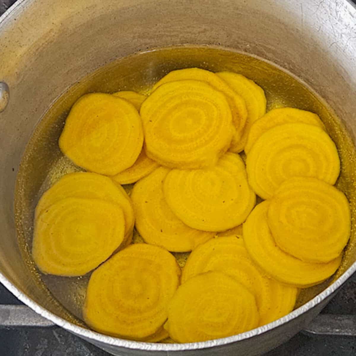 Peeled and sliced golden beets in a pot of water for the roasted asparagus and fennel salad with golden beets.