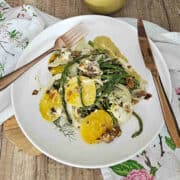 Roasted asparagus and fennel salad with golden beets on a plate with a fork and knife ready to eat.