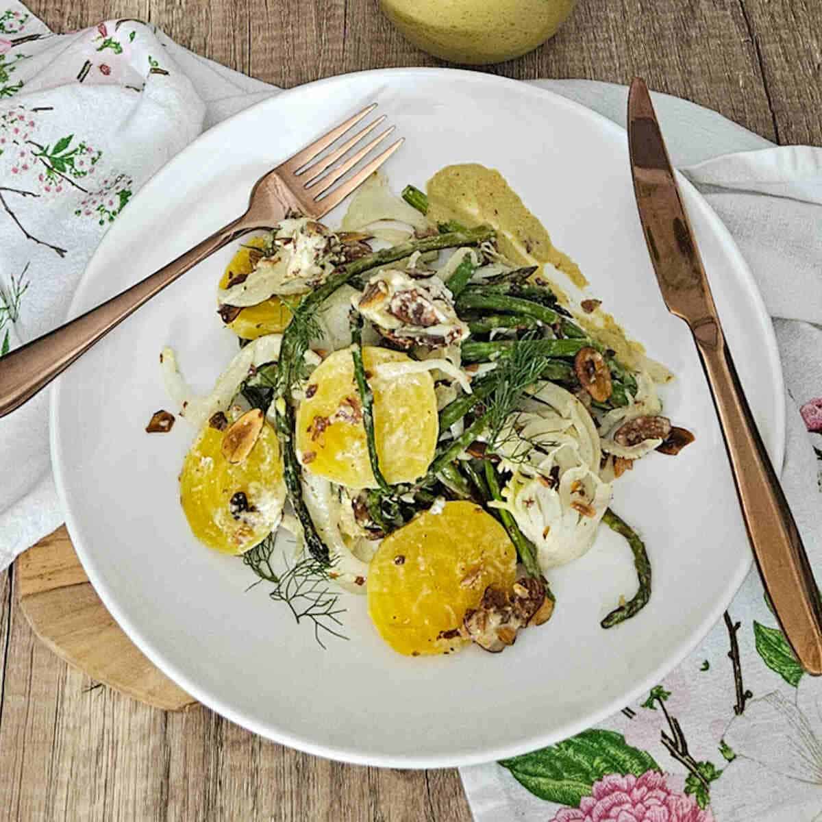 golden beet asparagus and fennel salad on a plate with a fork and knife.