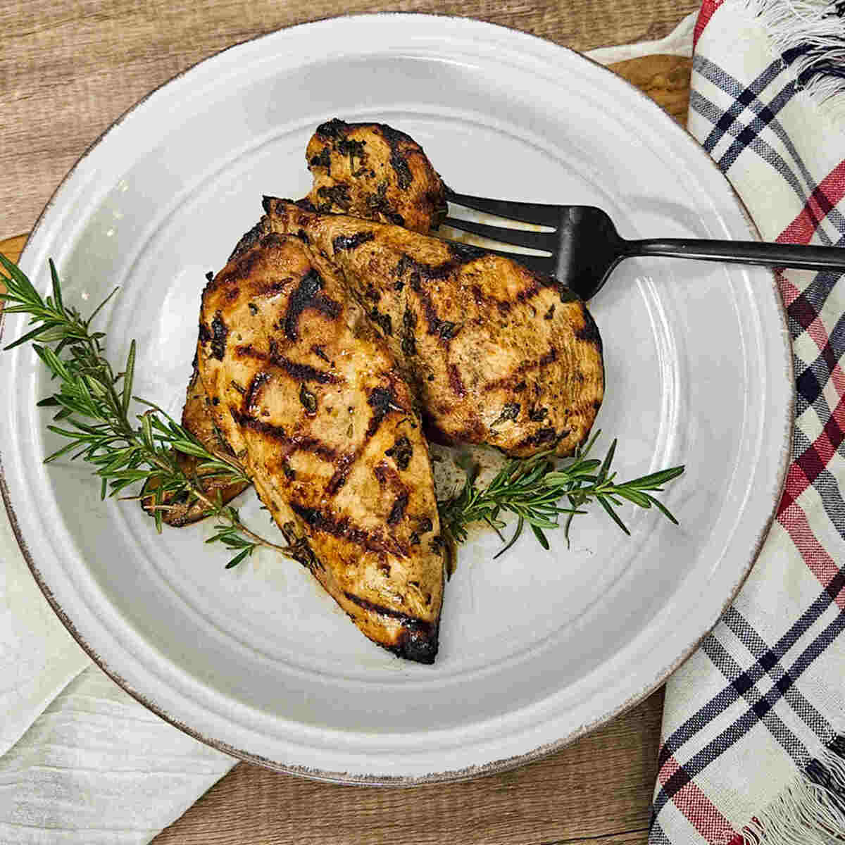 Grilled chicken on a white plate with a fork.