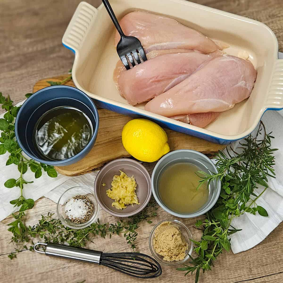 Ingredients for white balsamic herb marinated grilled chicken in a baking dish and on a cutting board.