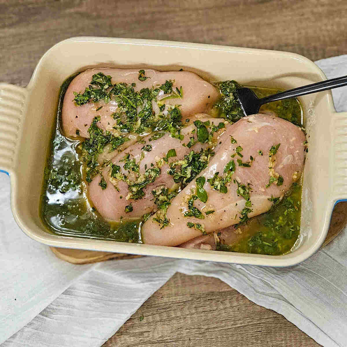 Chicken breasts in a baking dish with white balsamic herb marinade.