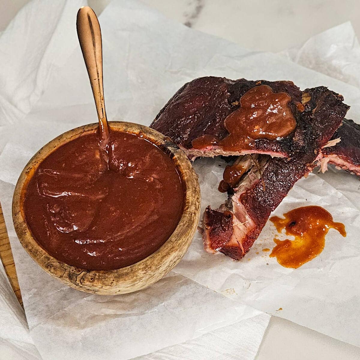 Bbq sauce in a wooden bowl with ribs.