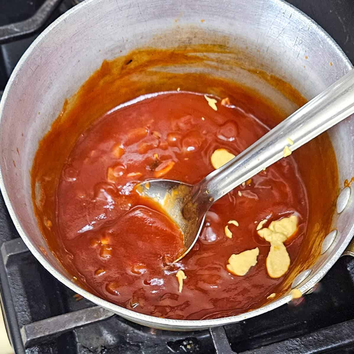 A pan filled with sauce and a spoon.