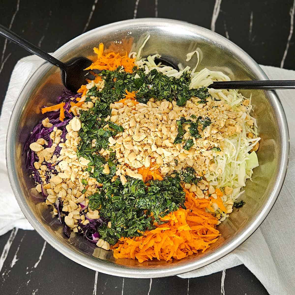A bowl of salad with carrots, cabbage, herb dressing and chopped peanuts.