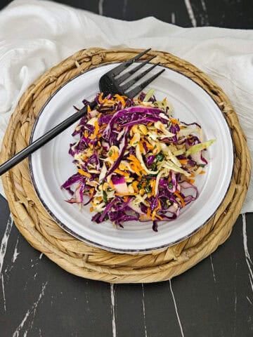 A plate of crunchy Thai style slaw on a plate and a fork.