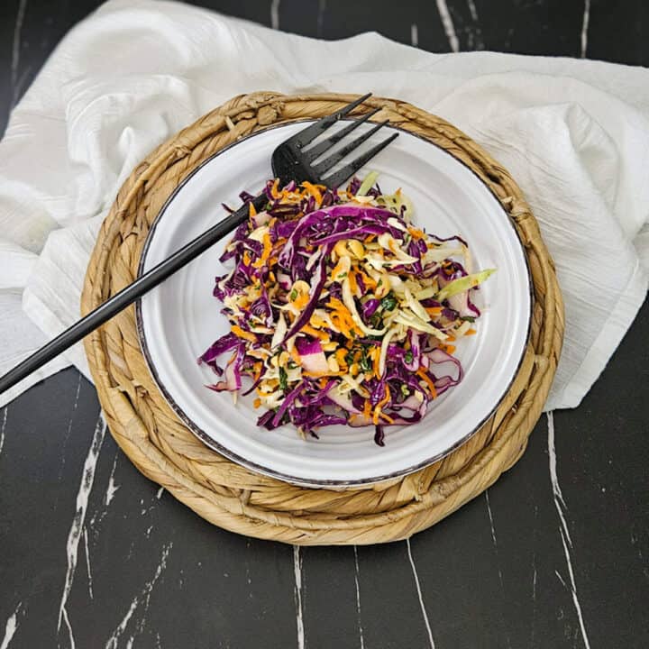A plate of crunchy Thai style slaw on a plate and a fork.