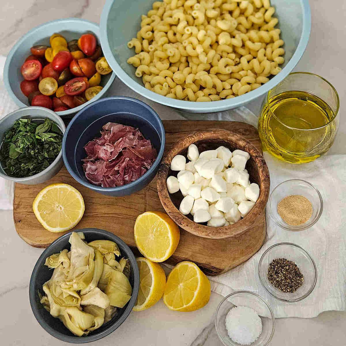 The ingredients for pasta salad on a cutting board.