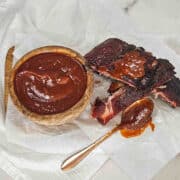 A pork ribs with Memphis BBQ sauce on a piece of white paper and a spoon.