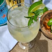 A glass of Thai garden spritz with lime and Thai basil leaves leaves.