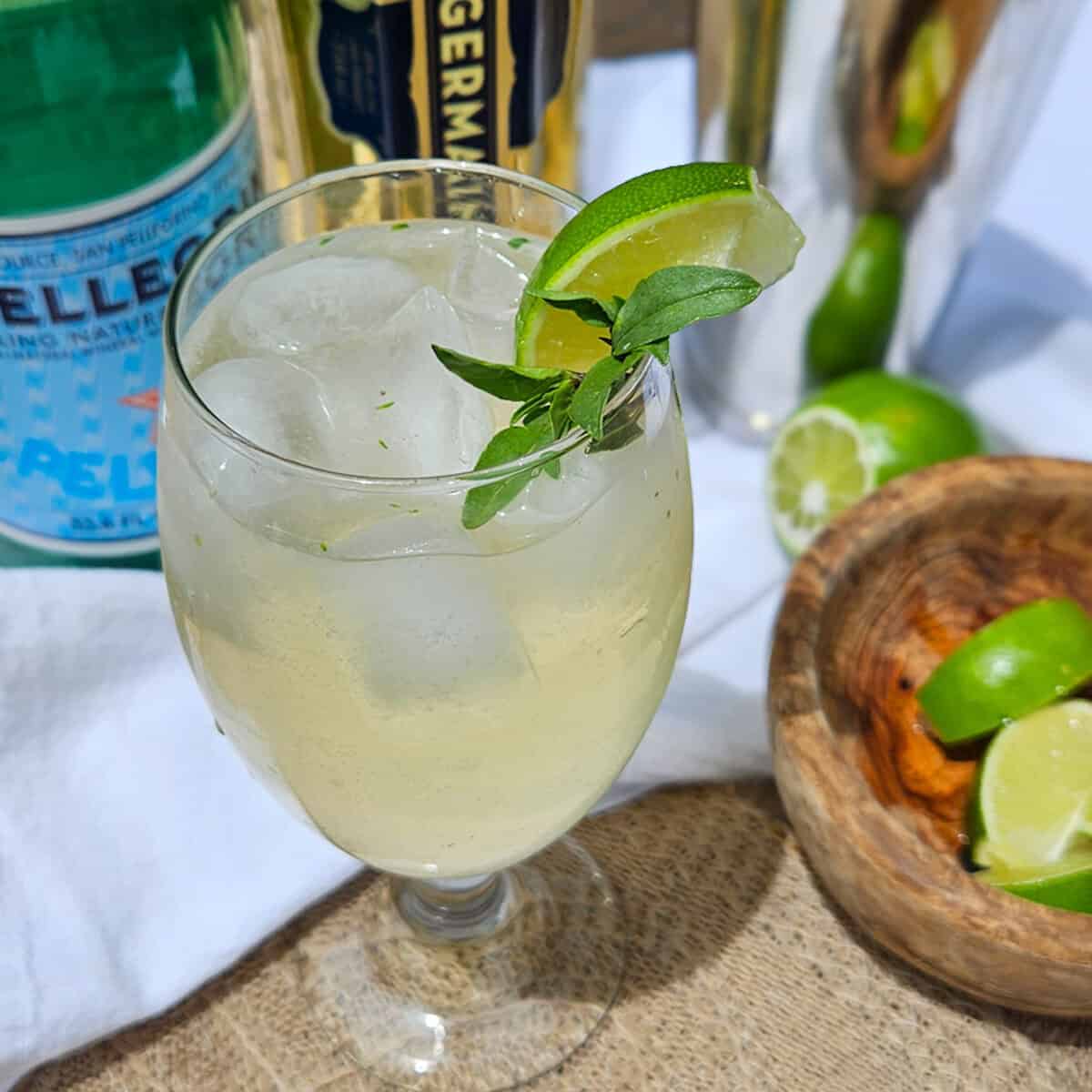 A glass of Thai garden spritz with lime and Thai basil.