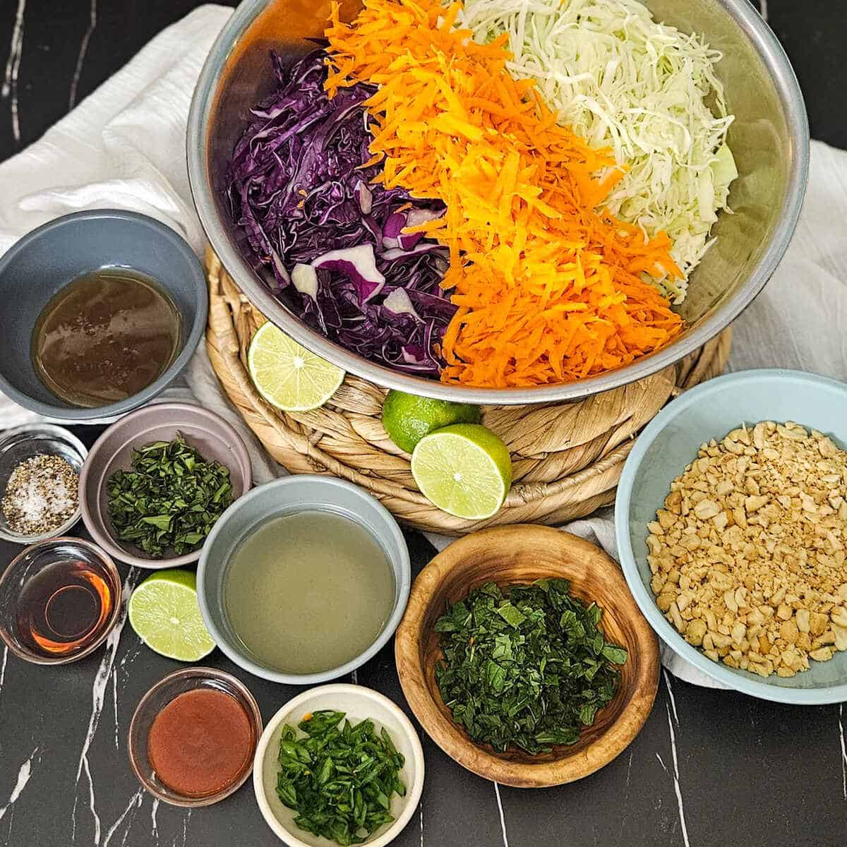 Ingredients for crunchy Thai style slaw with peanuts and lime in bowls.