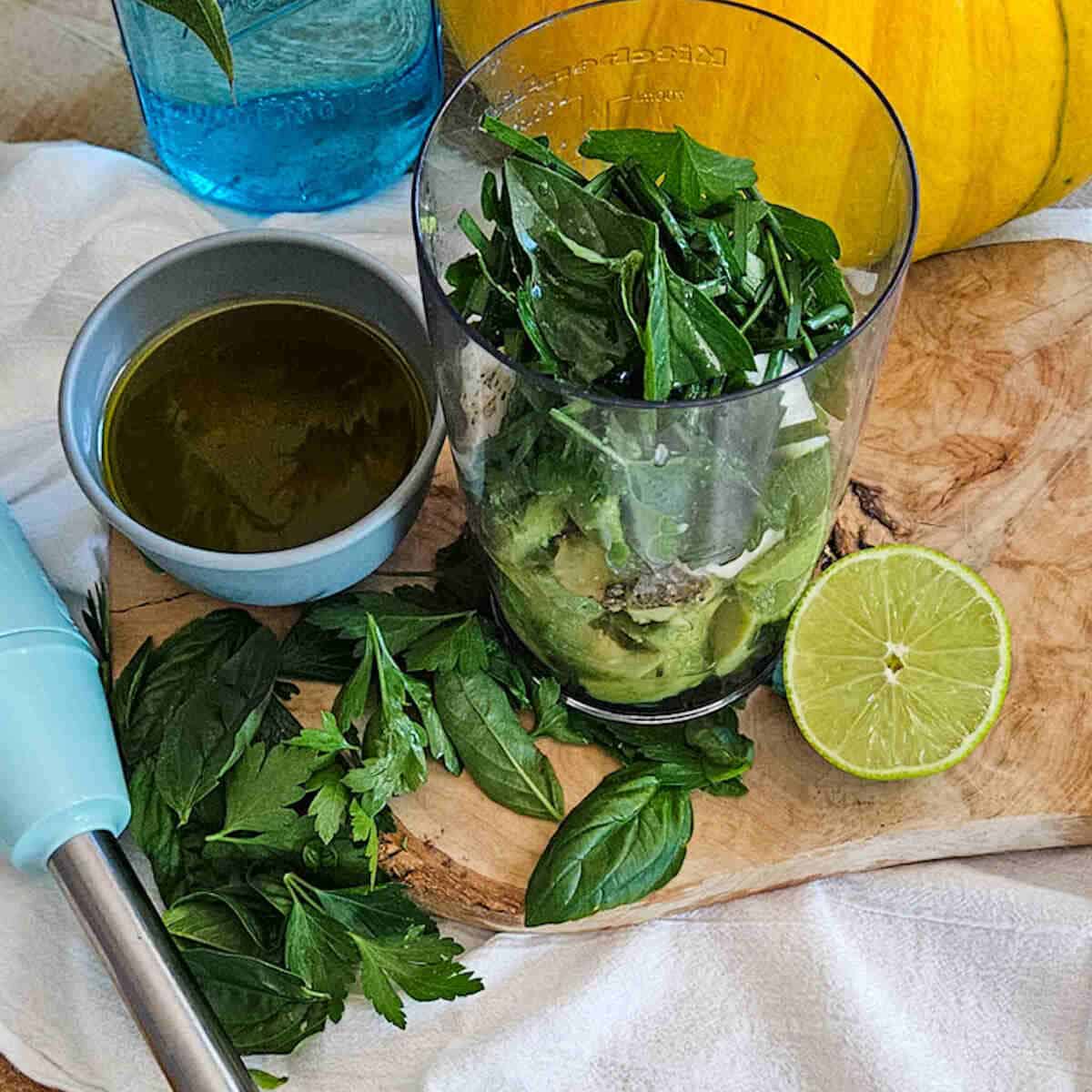 Fresh basil and herbs in a glass jar for creamy avocado dressing preparation.