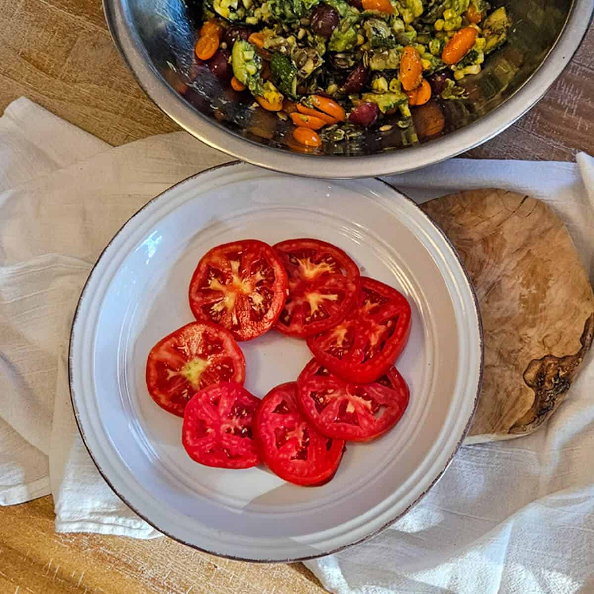Fresh sliced tomatoes on a white plate for salad or garnish for the grilled corn and zucchini salad