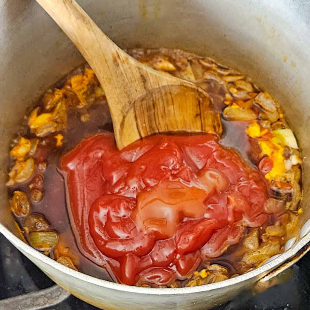 Kansas city BBQ sauce cooking with onions in a pot, perfect for homemade seasoning and flavor.