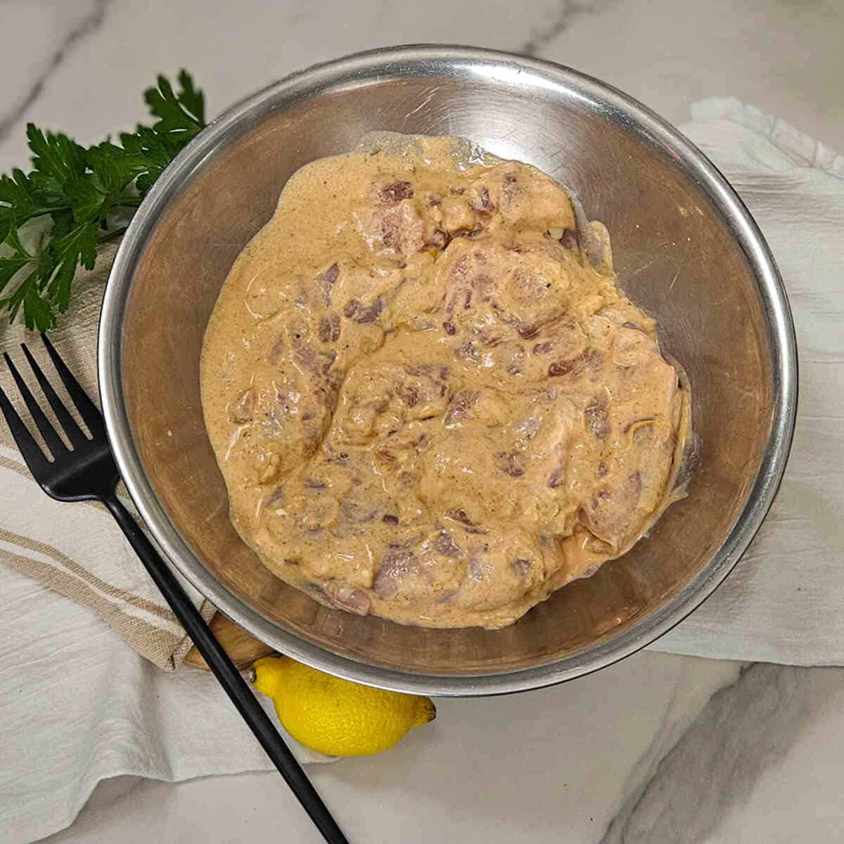 Greek yogurt marinated chicken in a bowl.
