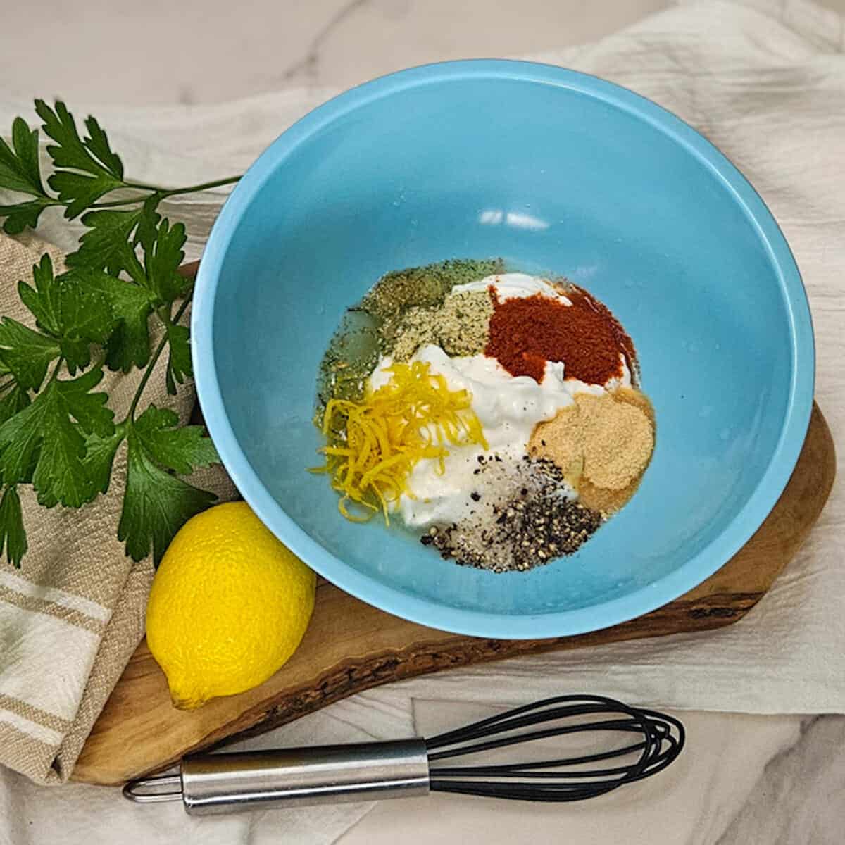 Season two taste, ingredients for Greek yogurt marinade, culinary spices, and herbs in a blue bowl.