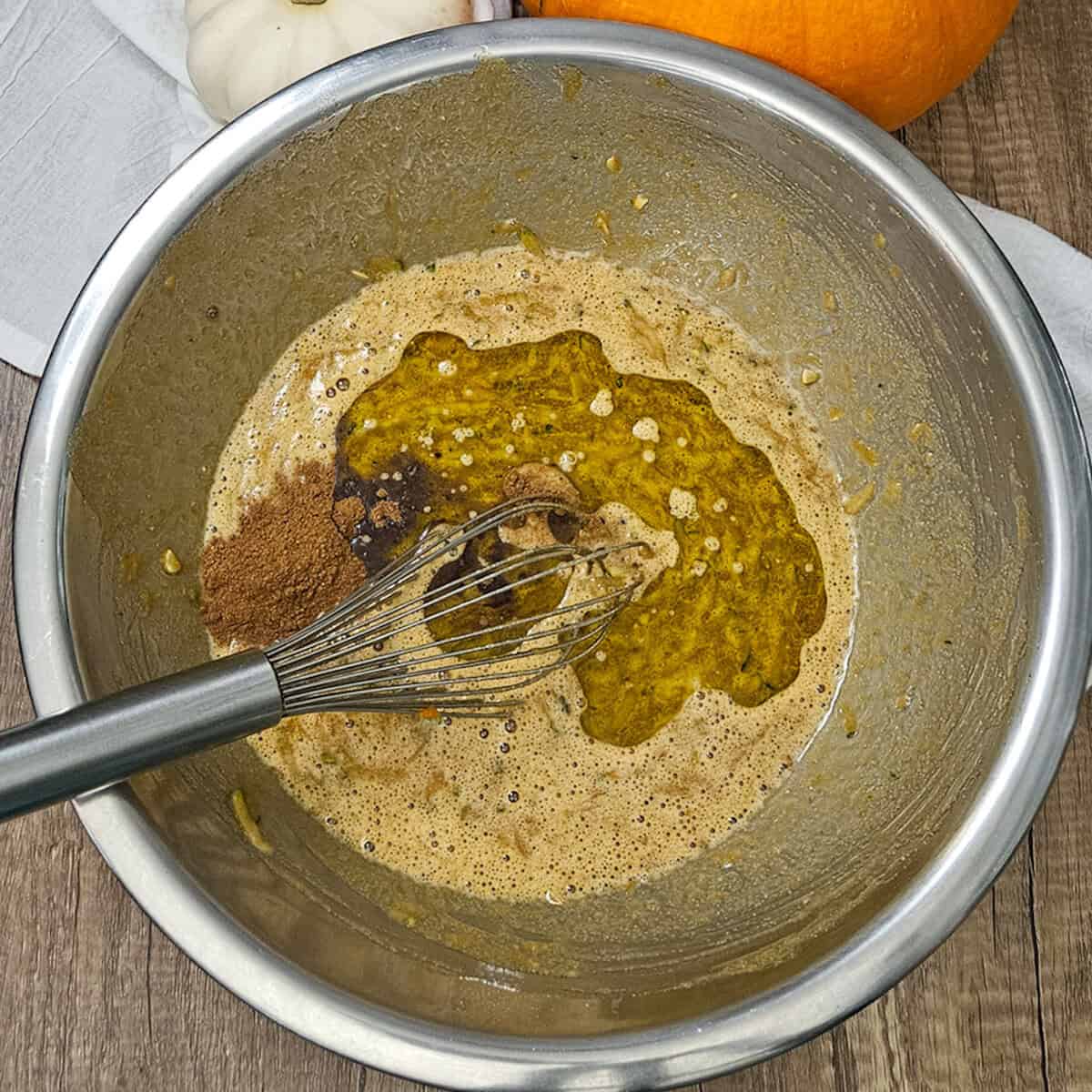 Adding oil and pumpkin spice to pumpkin spice zucchini bread batter.