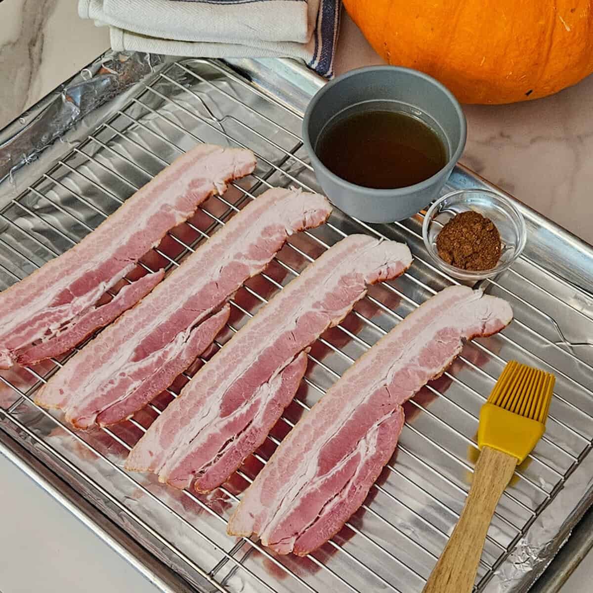 Savory bacon strips prepared for cooking with spices and seasonings on a wire rack.
