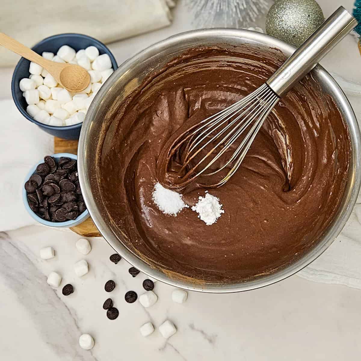 Rich chocolate hot cocoa brownie batter with marshmallows, chocolate chips, and baking ingredients.