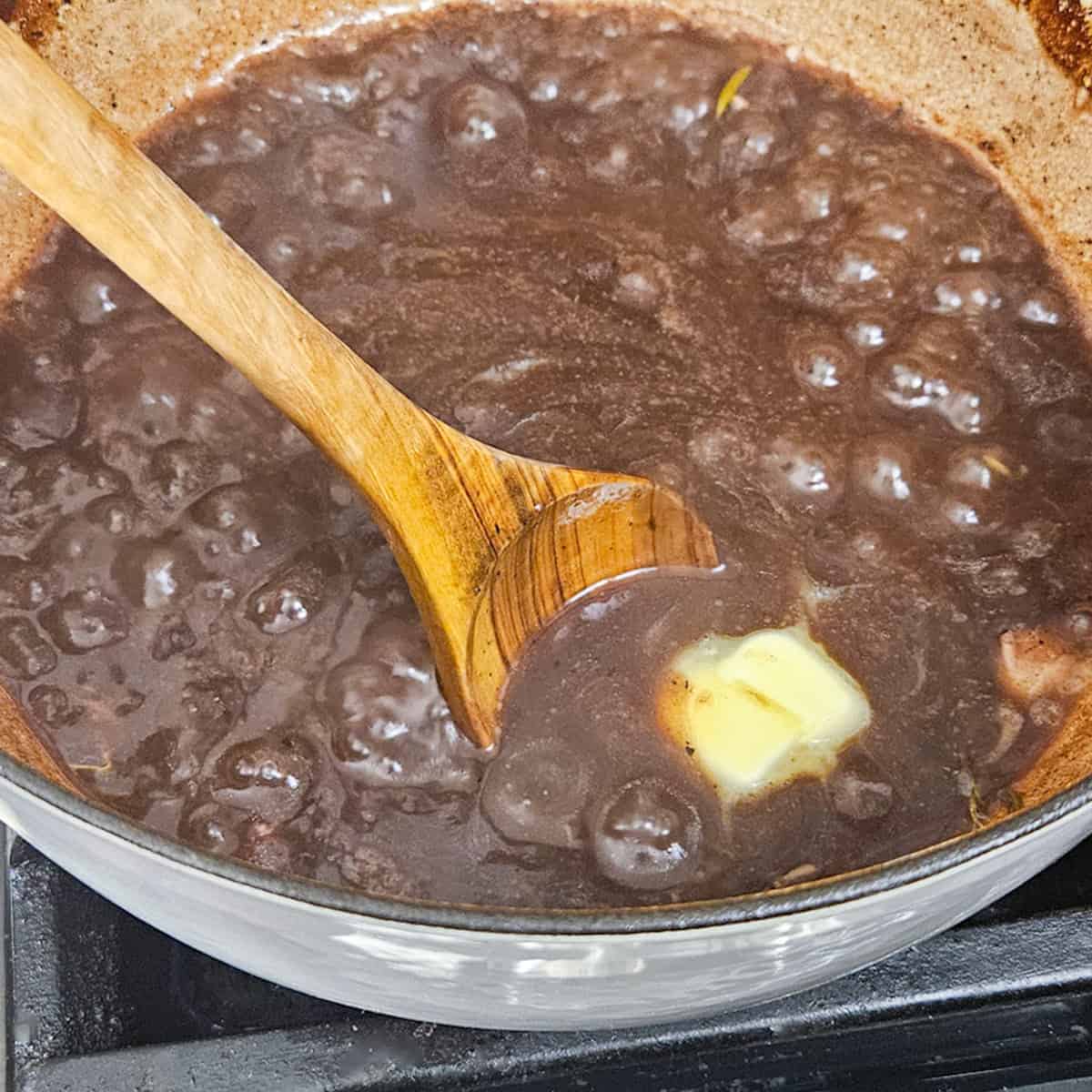 Adding butter to red wine gravy.