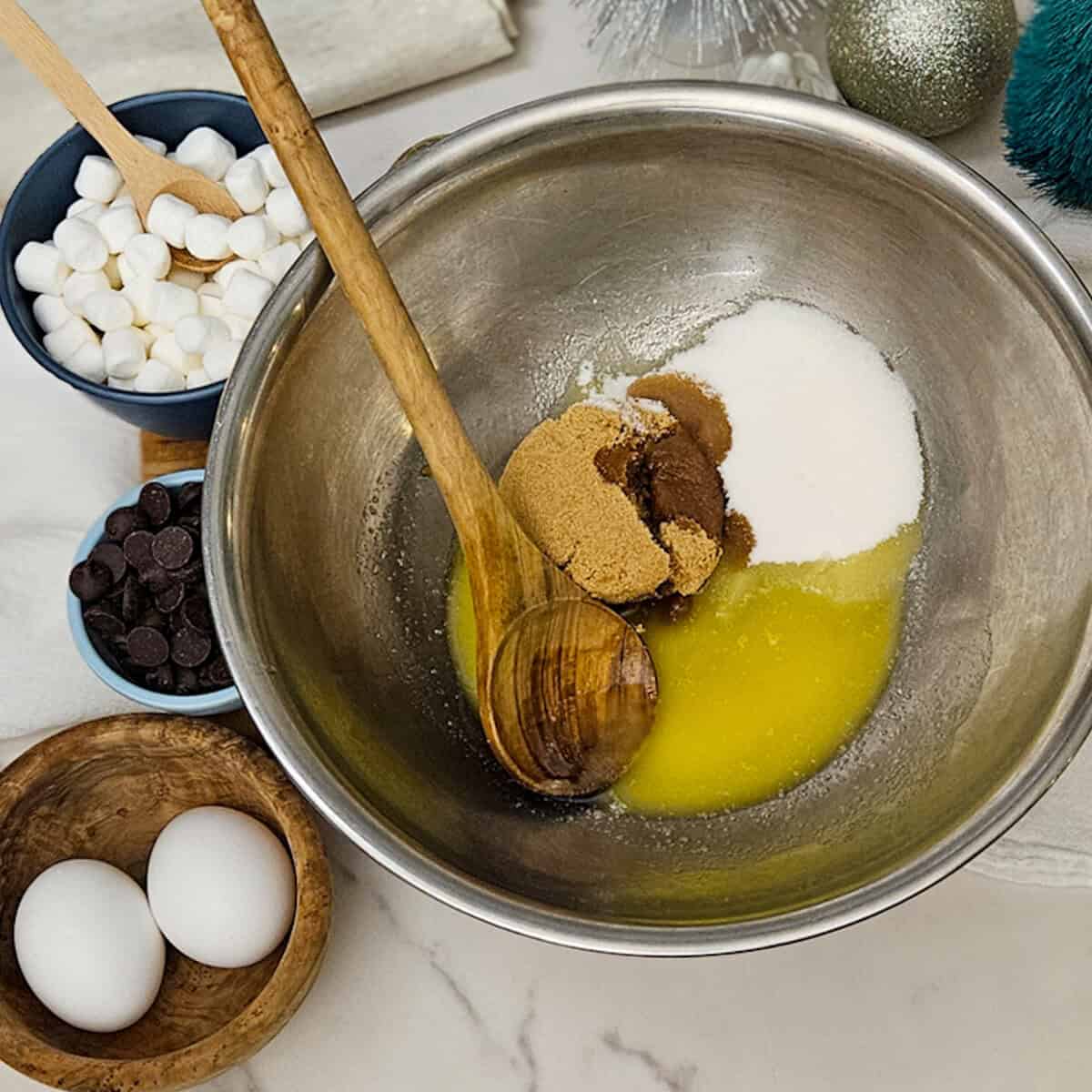 Combining sugars and melted butter for hot cocoa brownie mix.