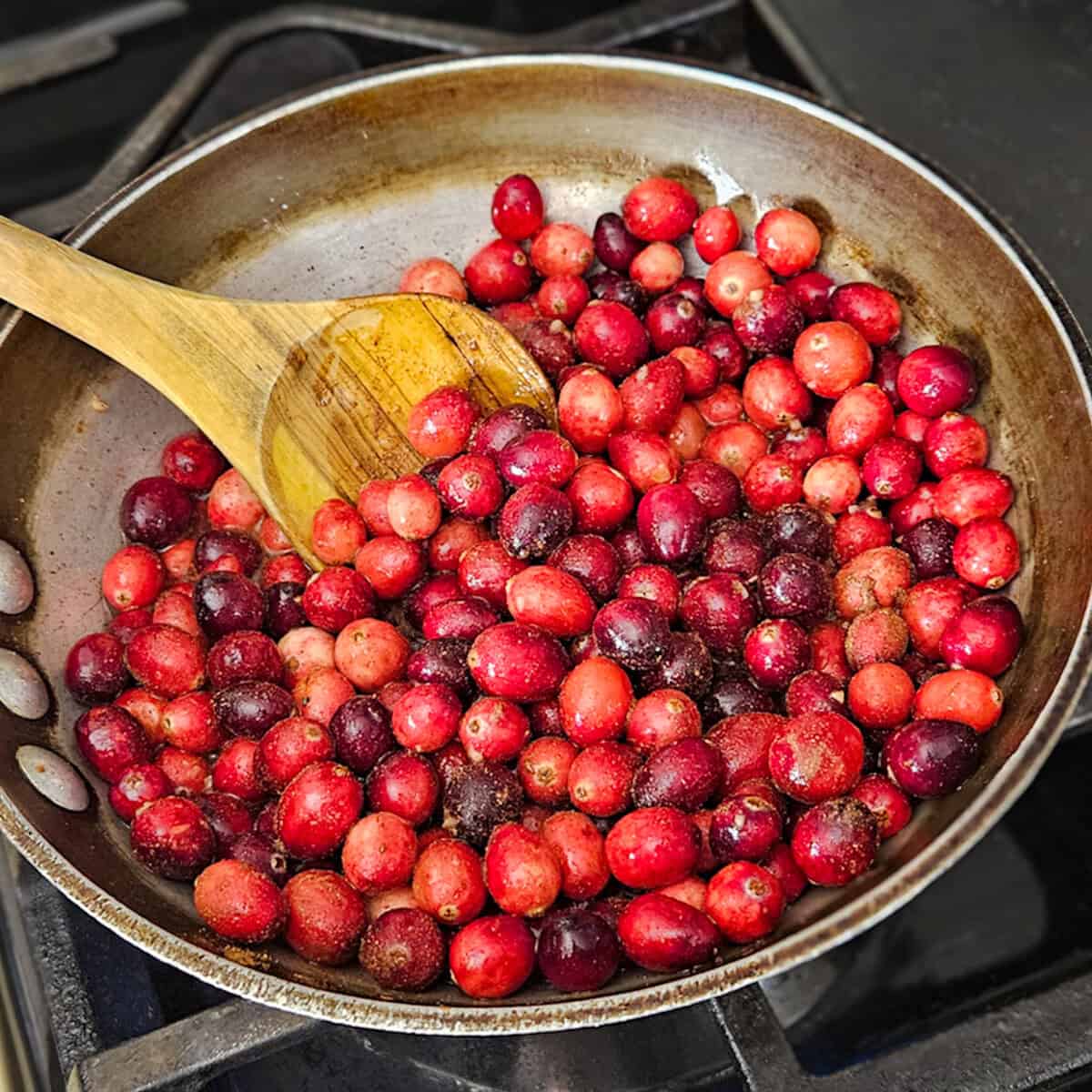 Fresh red cranberries being cooked in a skillet, perfect for seasonal recipes.