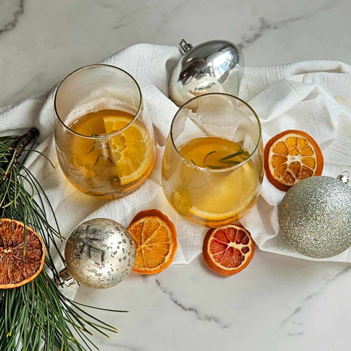 Delicious holiday beverages garnished with orange slices and rosemary, perfect for celebrations.