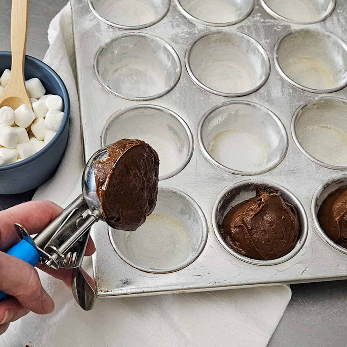 Alt text: Filling cupcake molds with rich chocolate hot cocoa brownie batter for baking.