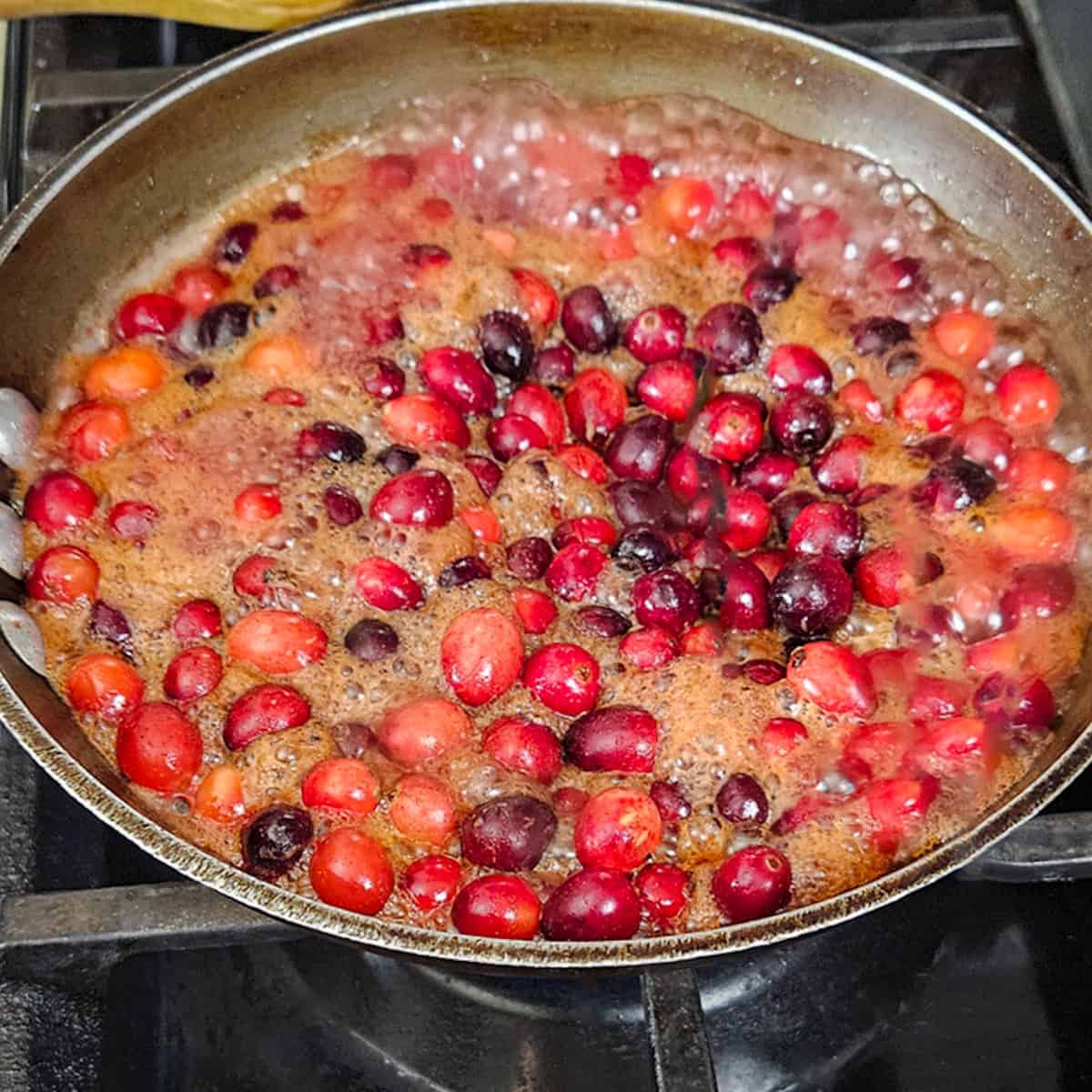 Cranberry sauce being cooked on stove with pomegranate and tangerine juice.