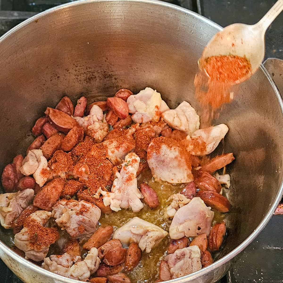 Adding seasoning to the gumbo cooking in a pot on the stove.