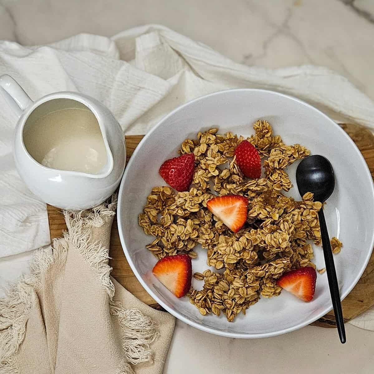 Chai spice granola topped with strawberries and, served with a side of milk.
