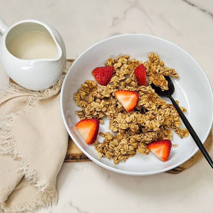 Crunchy homemade granola with fresh strawberries in a white bowl.